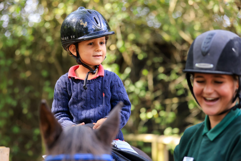 A kid enjoying a pony ride with staff